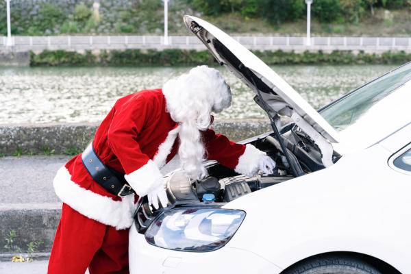 Image of Santa fixing a car outside in the snow