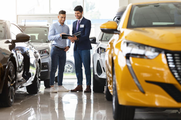 A car salesman showing a prospective buyer or leaser information about various vehicles