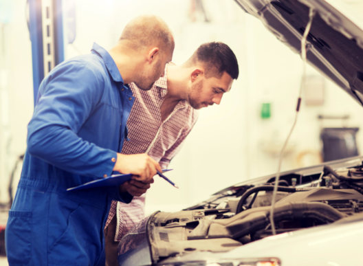 Two men discussing in front of an open hood of a car